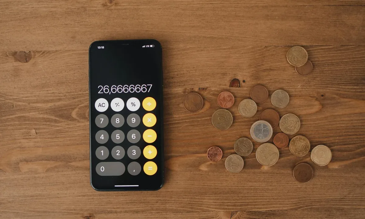 Calculator on a phone beside coins, representing website cost planning