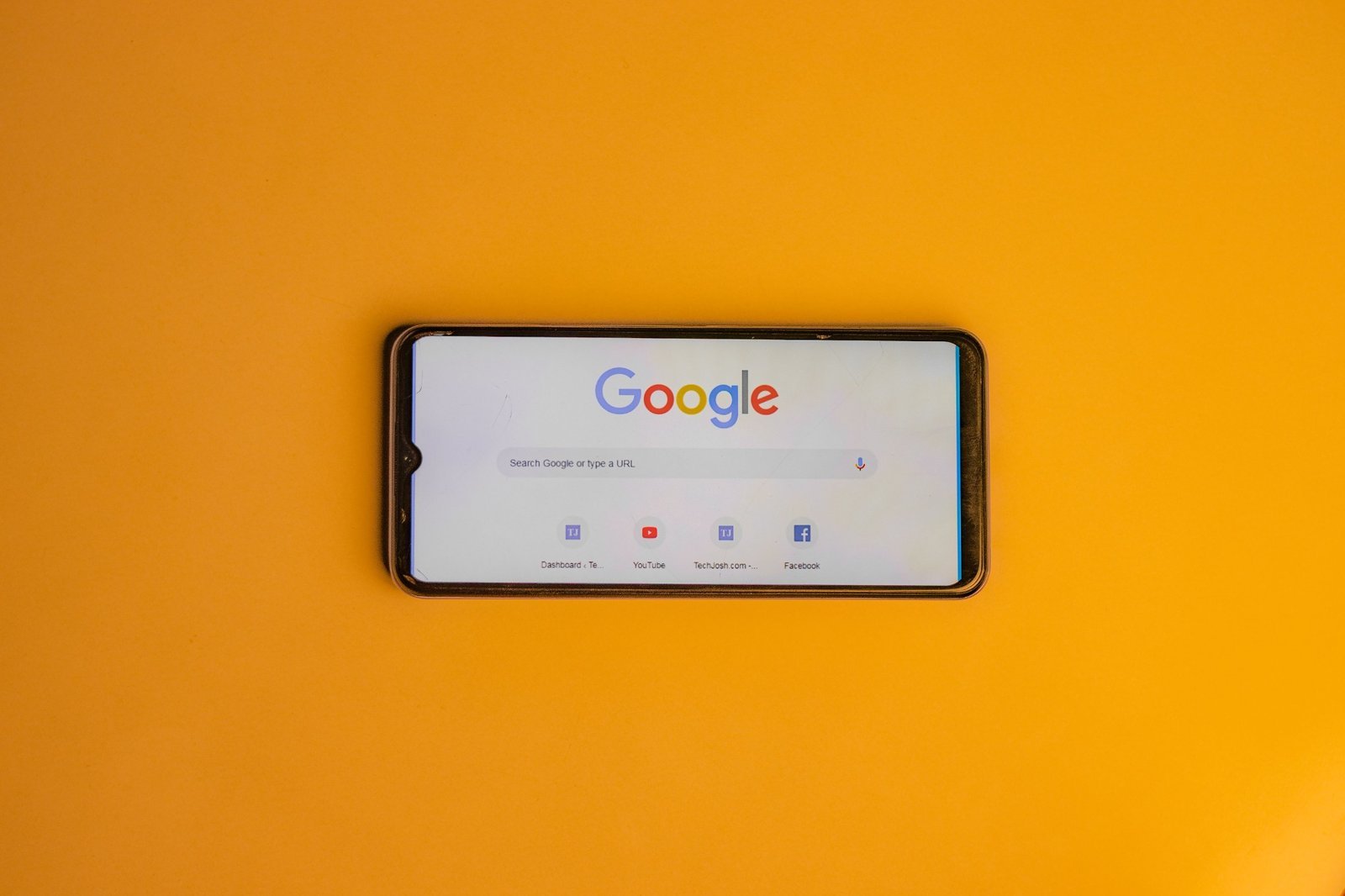 Smartphone displaying Google Search on a yellow background.