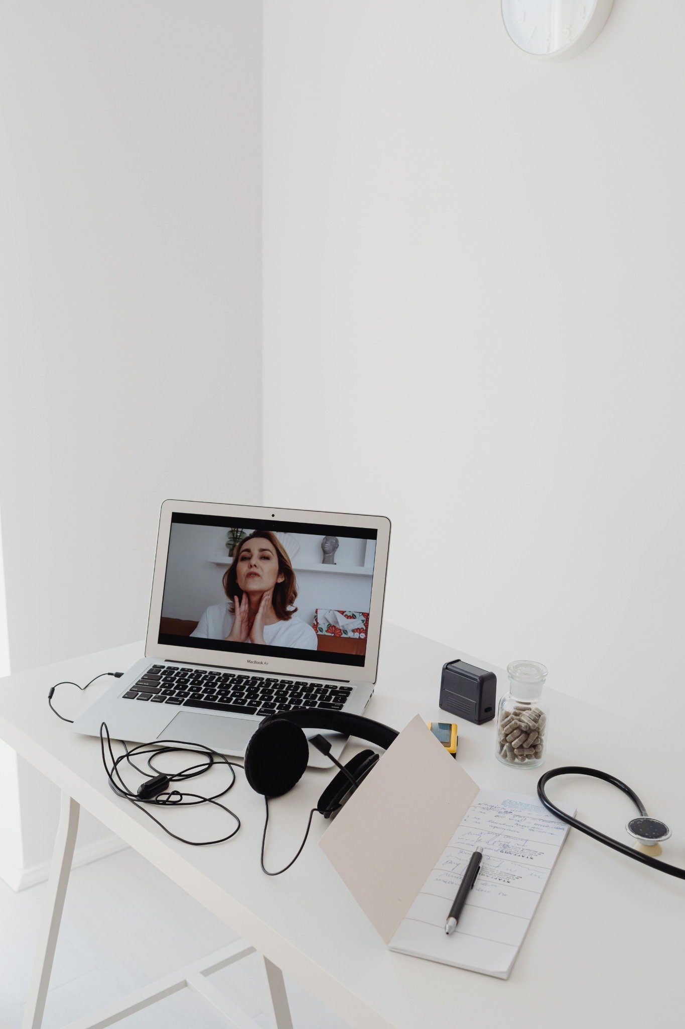 Laptop video consultation beside a stethoscope and medical notes, illustrative photography